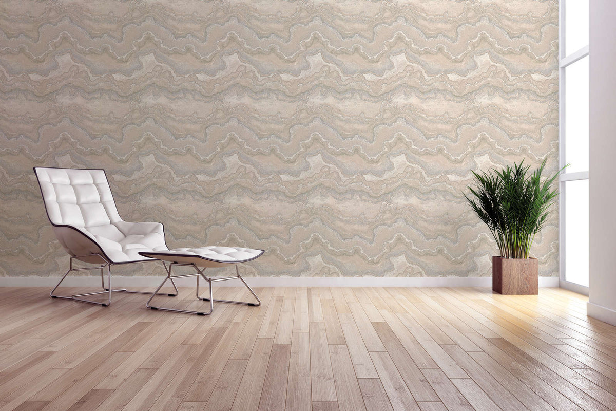 The Travertine Tide | Sand Pearl Luxe wallpaper hung behind a white lounge chair and potted plant on a timber floor