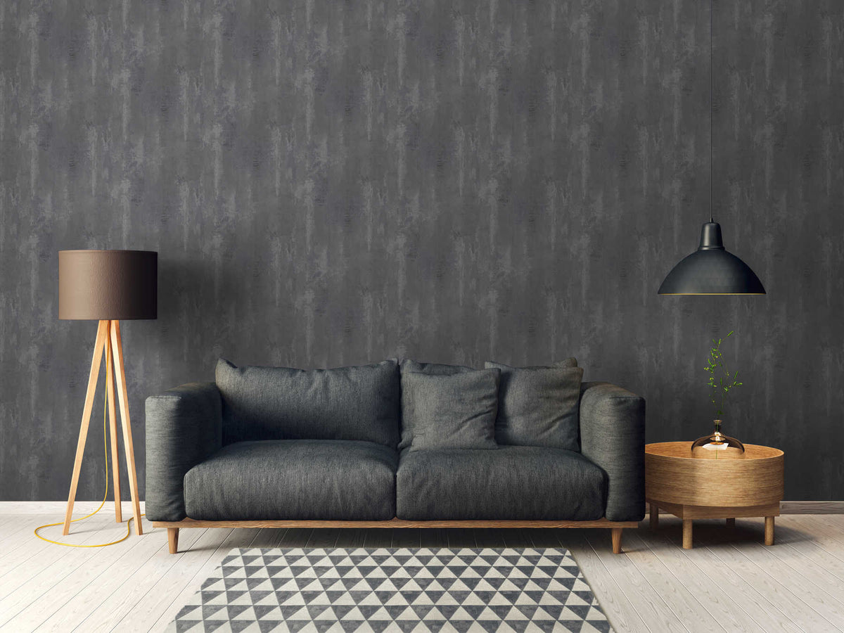 The Basalt Foundry | Charcoal Slate Luxe wallpaper behind a charcoal sofa, tripod lamp and patterned rug