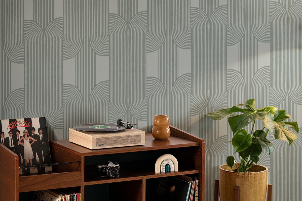 The Arcade Curve wallpaper in soft sage as a backdrop to styled furniture