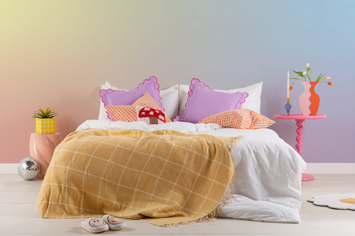 The Aurora Wash mural in sorbet rainbow behind the bed in a bedroom