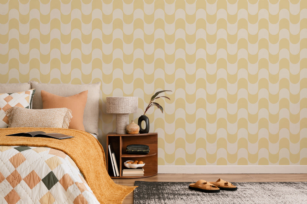 The Boardwalk Wave wallpaper in butter yellow behind the bed in a bedroom