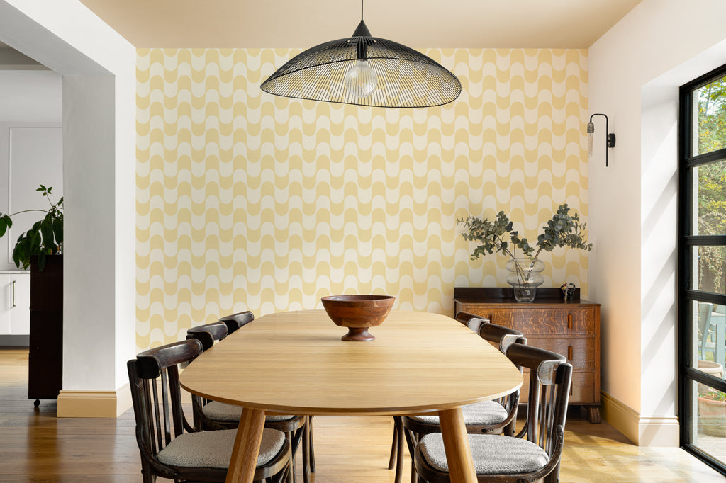 The Boardwalk Wave wallpaper in butter yellow behind a dining table