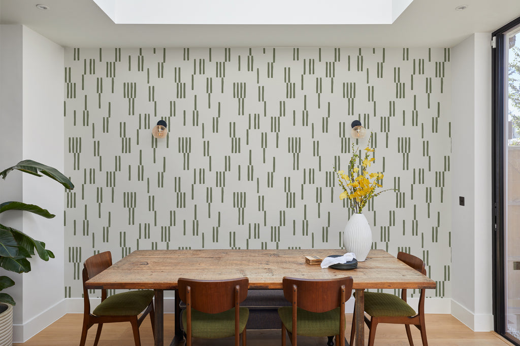 The Brushmark Column wallpaper in mossy green behind a dining table