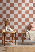 The Brushstroke Chequer wallpaper in terracotta behind a dining table