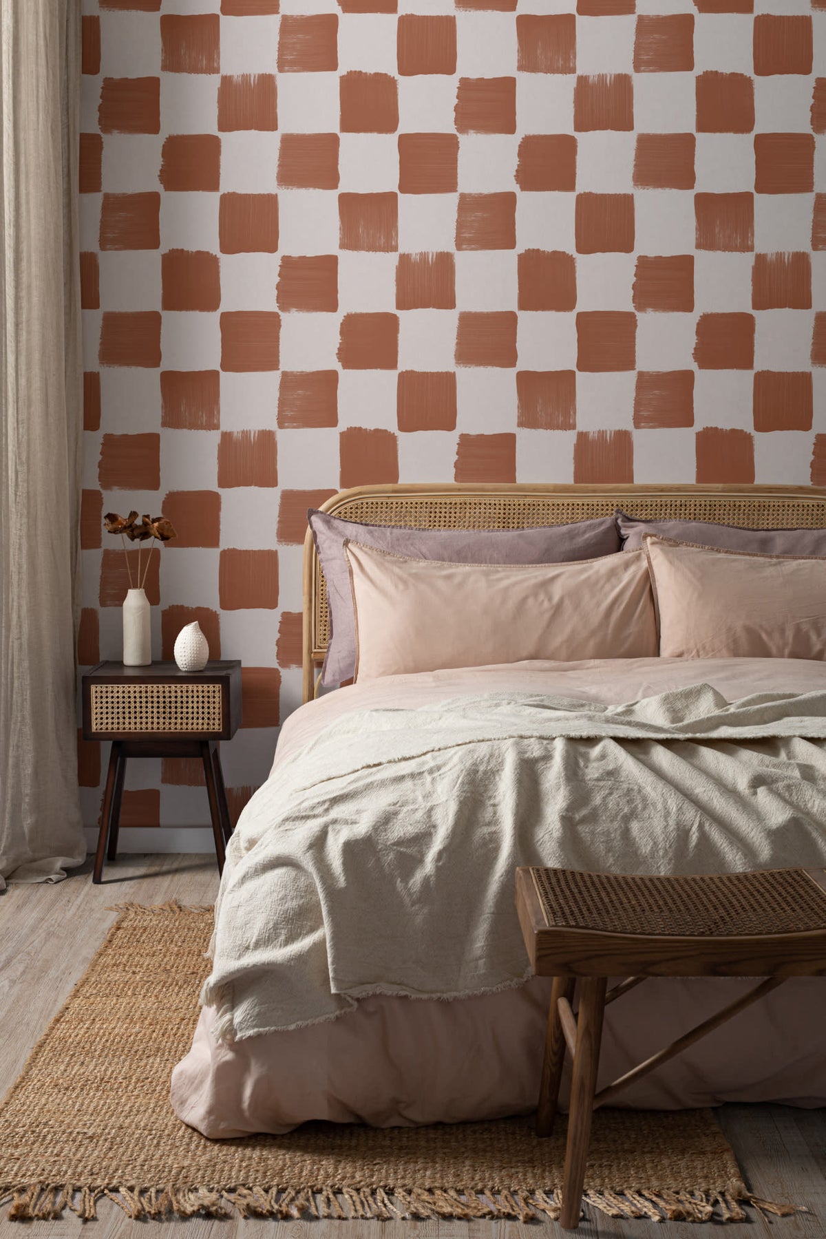 The Brushstroke Chequer wallpaper in terracotta behind the bed in a bedroom