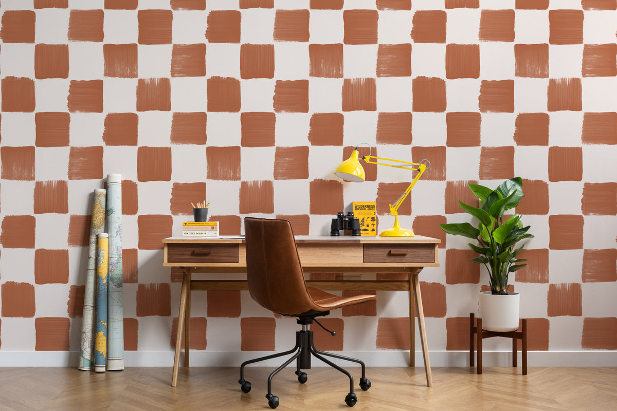 The Brushstroke Chequer wallpaper in terracotta behind a desk in a home office
