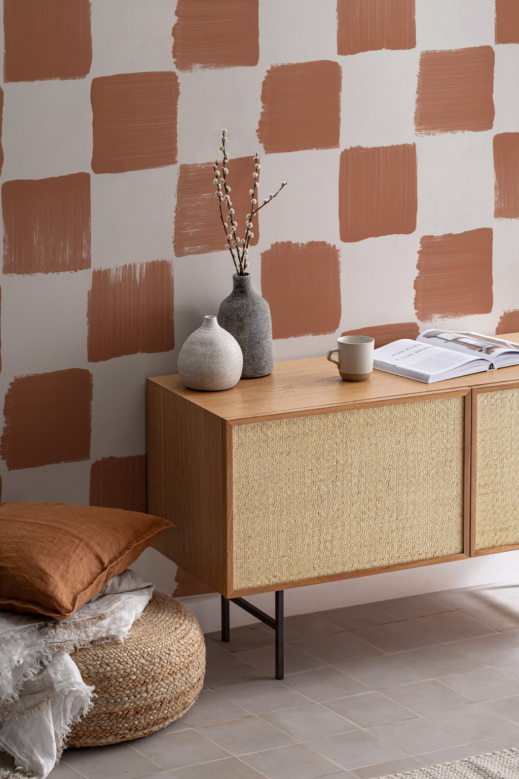 The Brushstroke Chequer wallpaper in terracotta as a backdrop to styled furniture