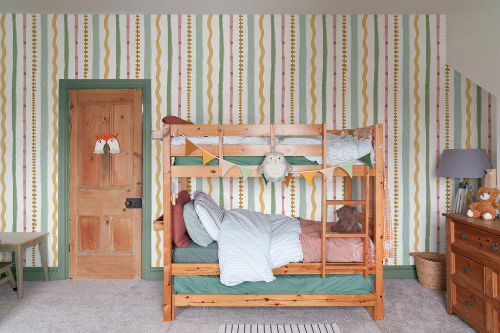 The Carousel Stripe mural in blush and pistachio on a nursery wall