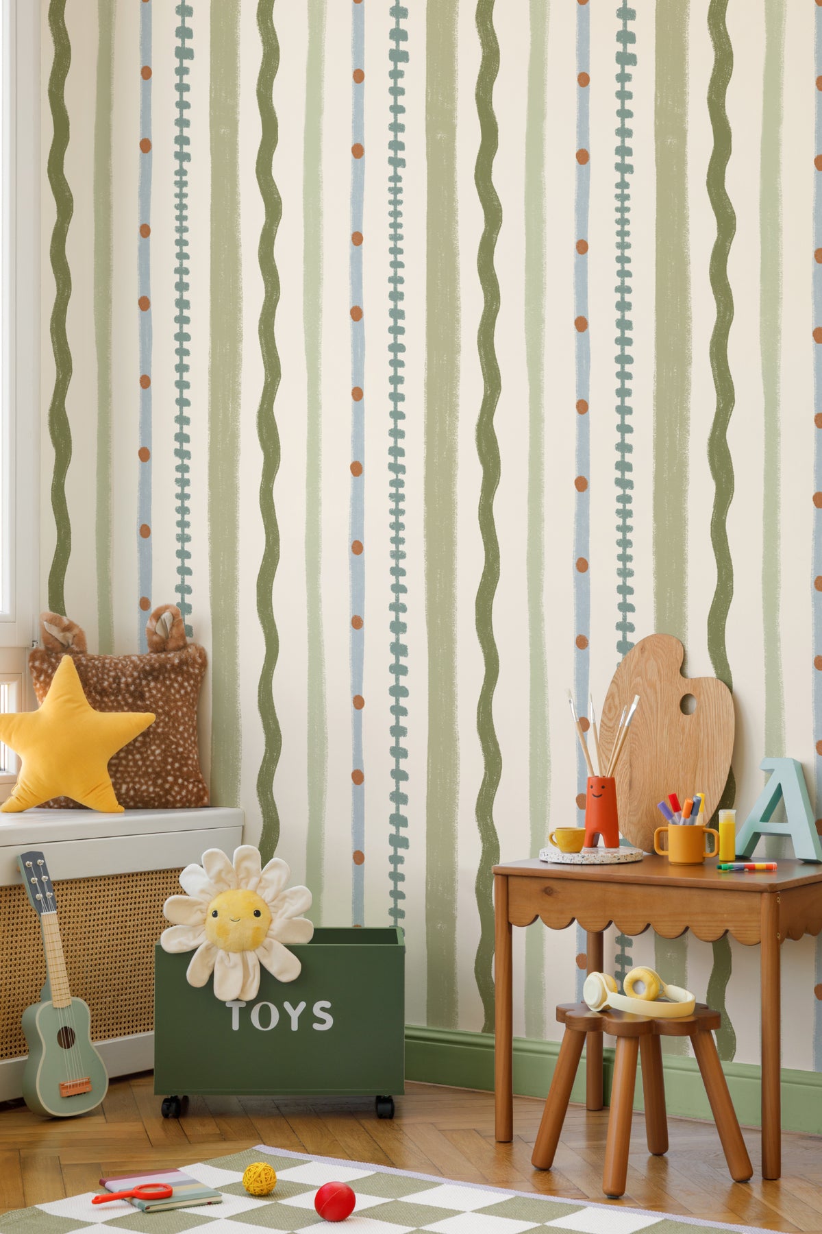 The Carousel Stripe mural in fern green and sand behind a kids' play corner