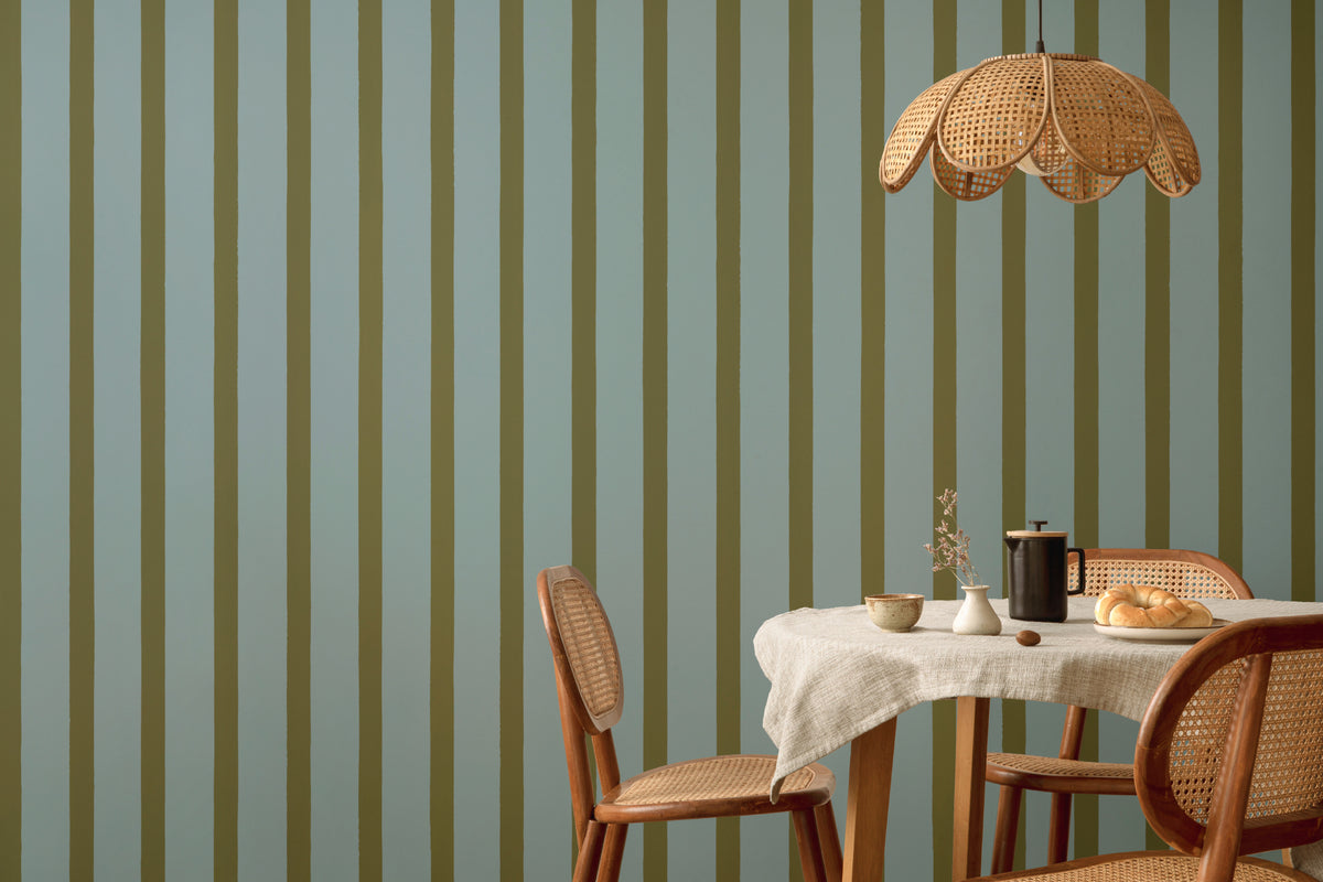 The Deckchair Stripe mural in sage and denim behind a dining table