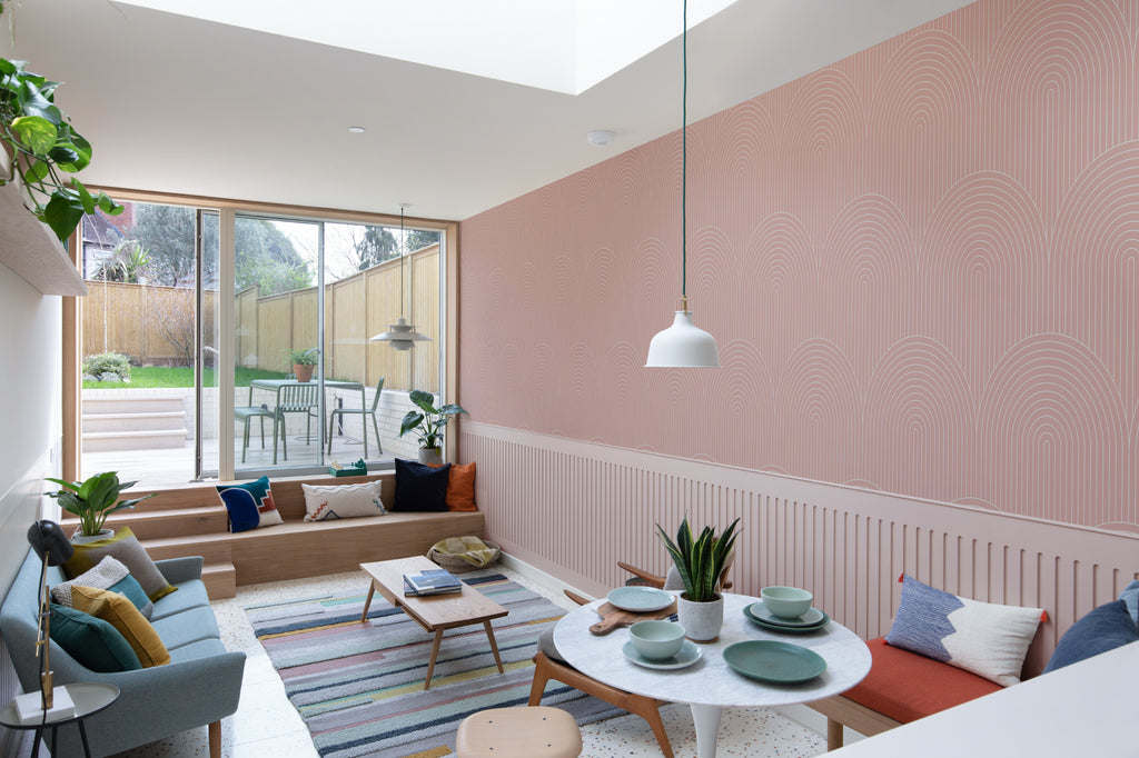 The Deco Archway wallpaper in dusty rose behind seating in a living room