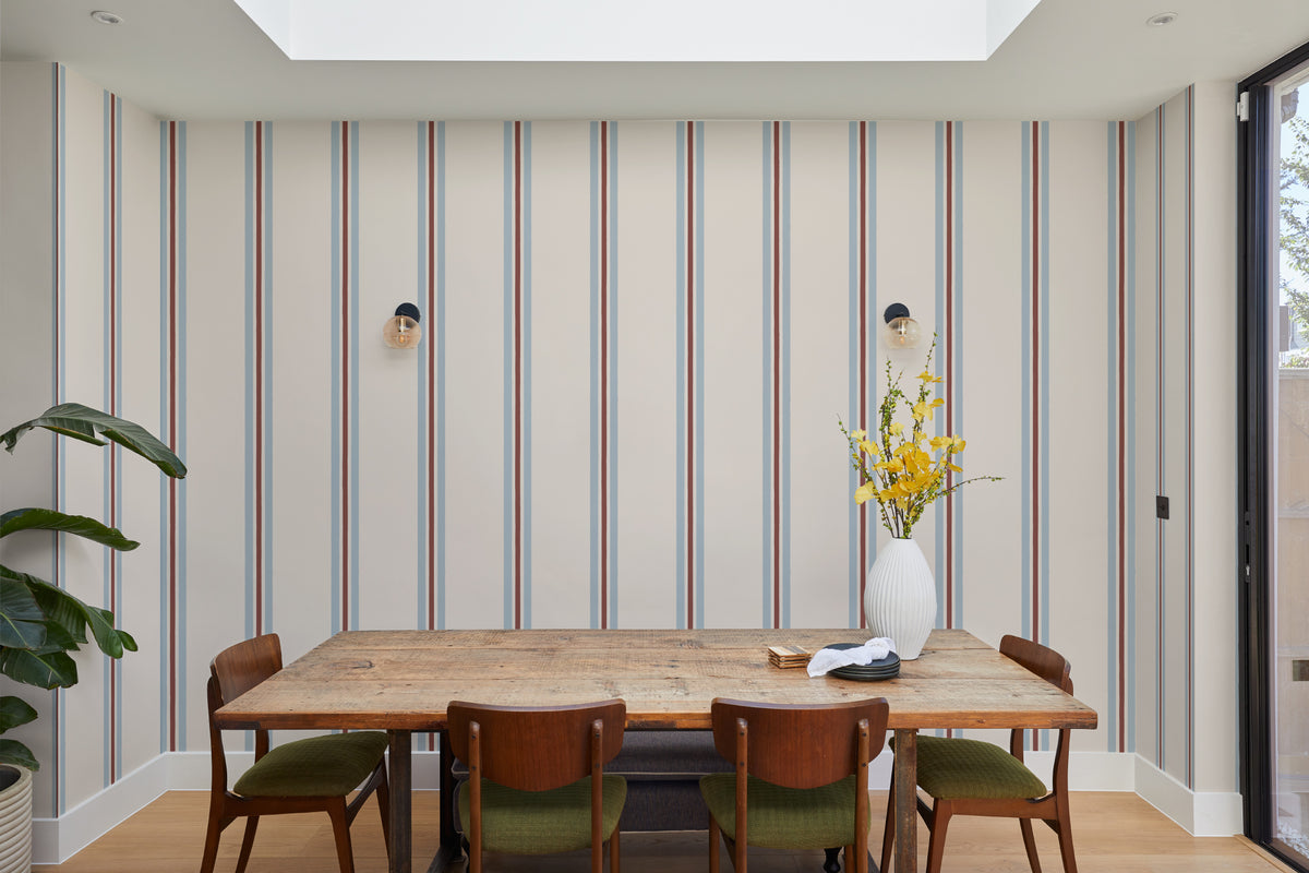 The Draughtsman Stripe wallpaper in sky blue behind a dining table