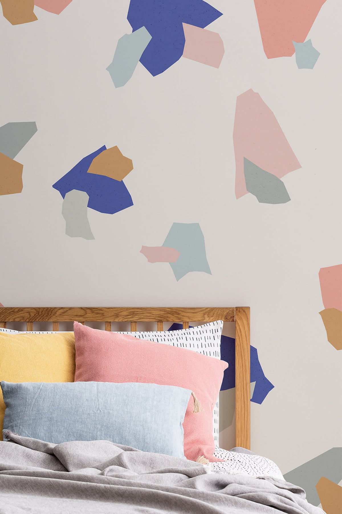 The Gallery Terrazzo mural in cobalt and coral behind the bed in a bedroom