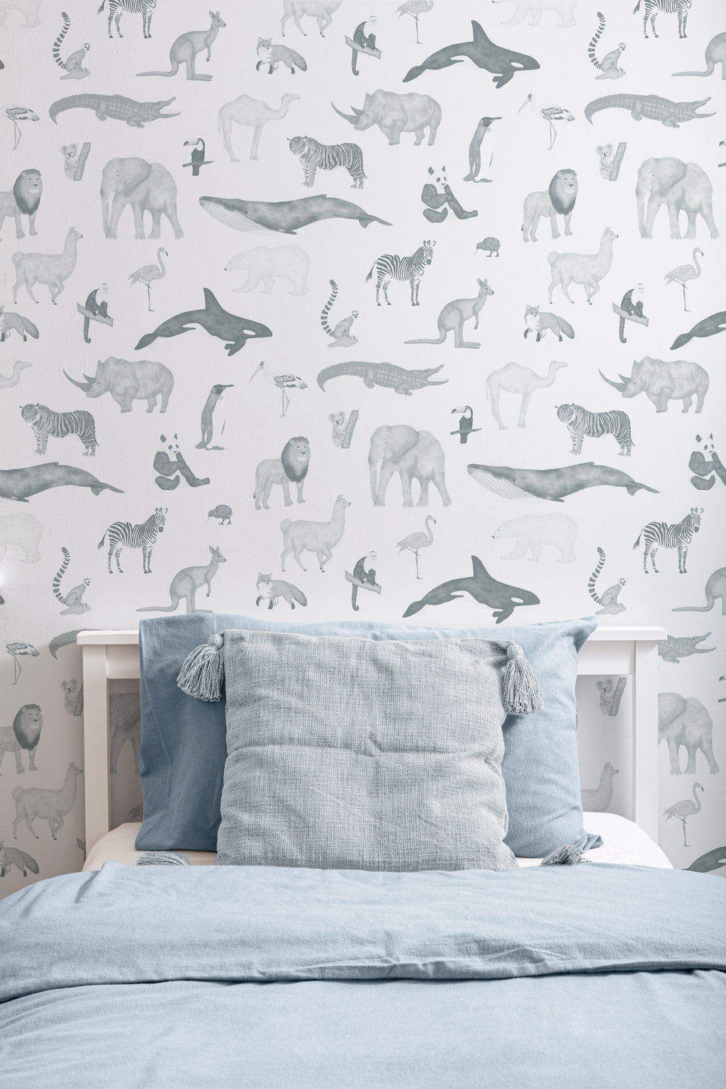 The Gentle Menagerie wallpaper in misty blue behind the bed in a bedroom