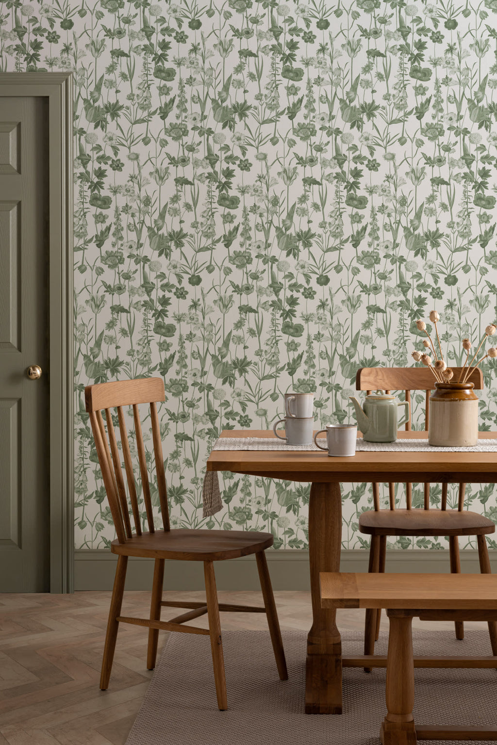 The Hedgerow Botanica wallpaper in fern green and white behind a dining table