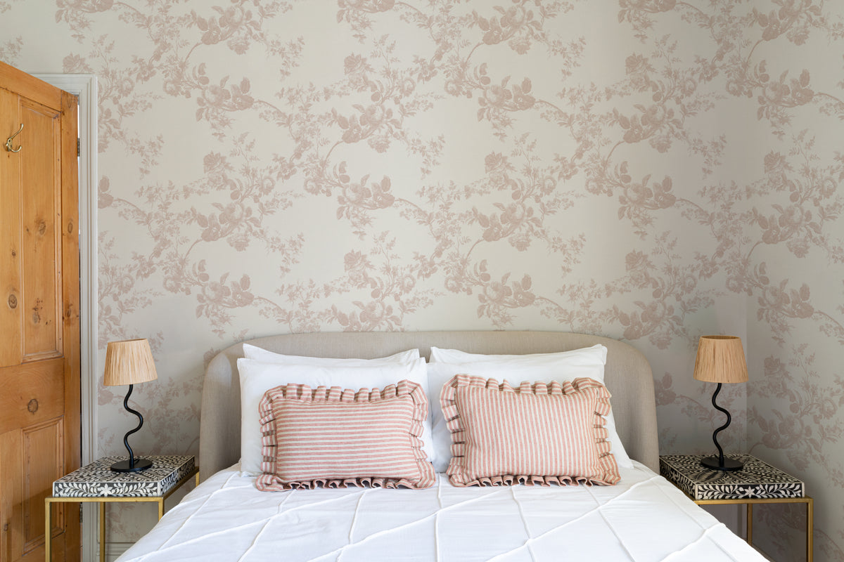 The Heirloom Rose mural in rose pink and white behind the bed in a bedroom