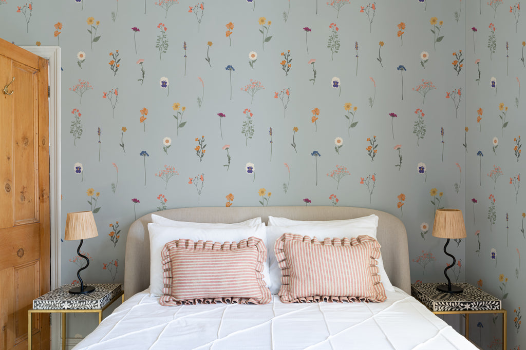 The Herbarium Press wallpaper in mist blue behind the bed in a bedroom