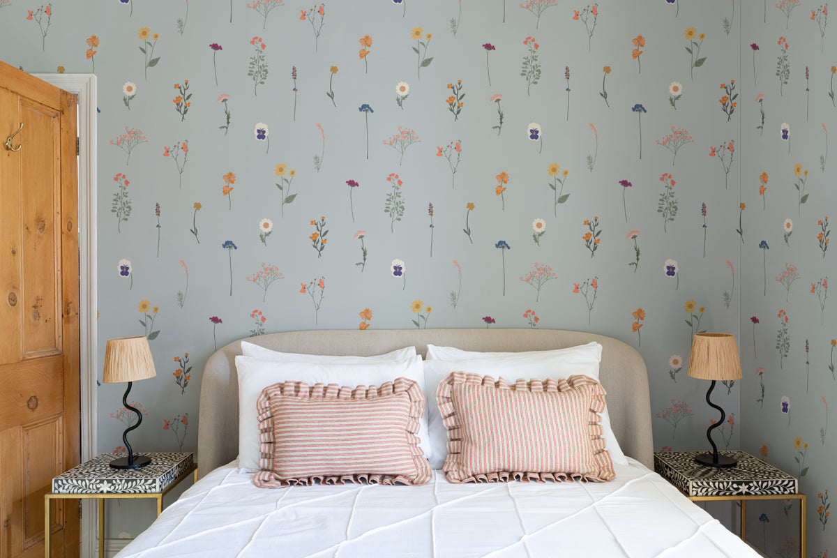 The Herbarium Press wallpaper in mist blue behind the bed in a bedroom