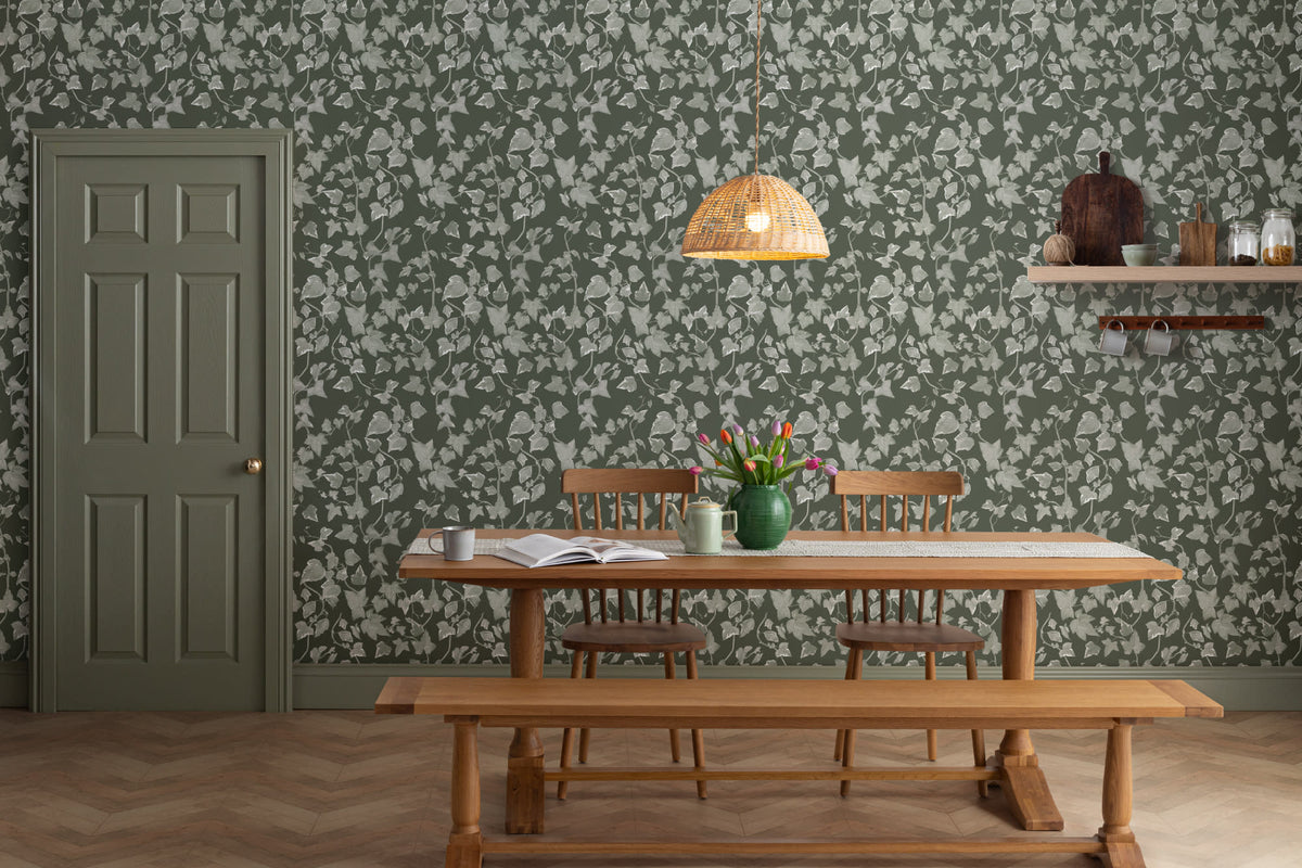 The Ivy Rectory wallpaper in forest green behind a dining table
