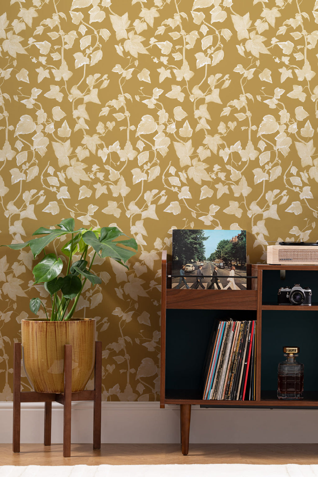 The Ivy Rectory wallpaper in mustard gold behind a styled console
