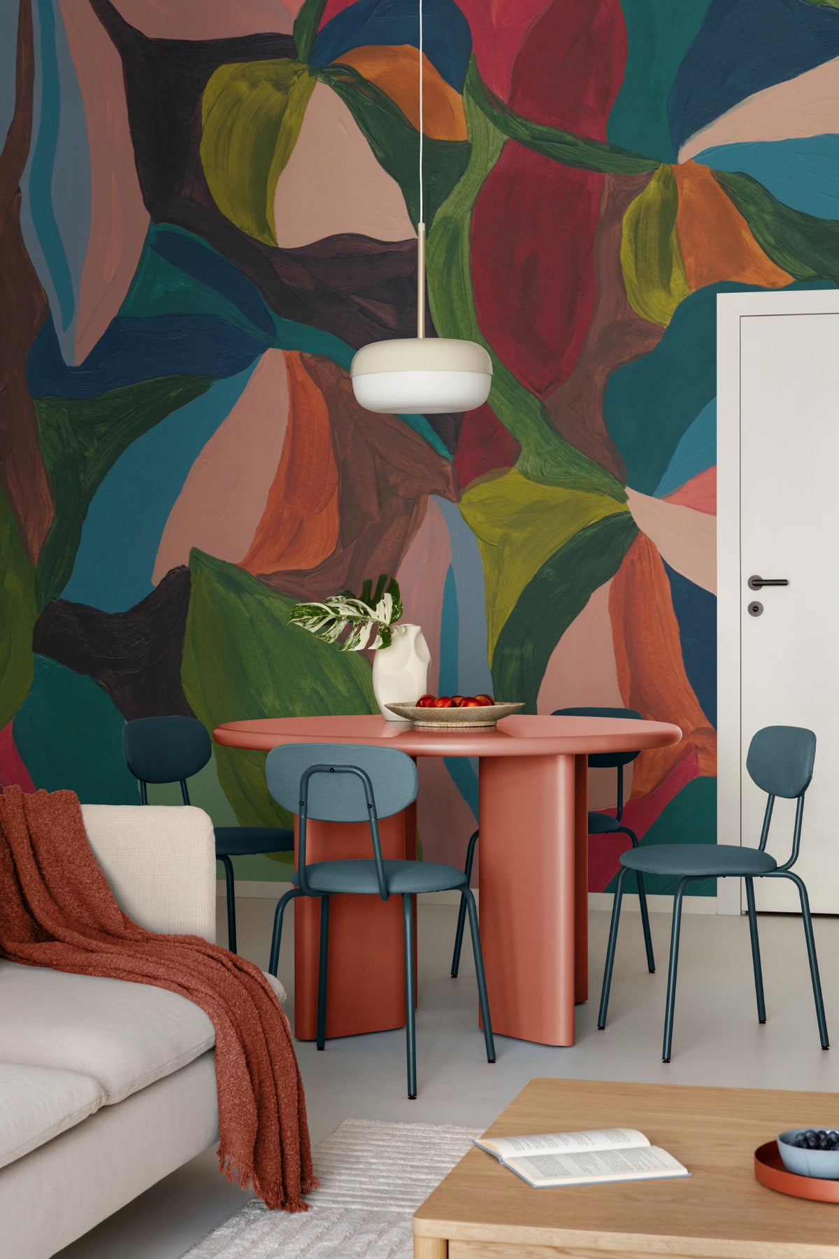 The Jewel Foliage mural in teal and coral behind a dining table