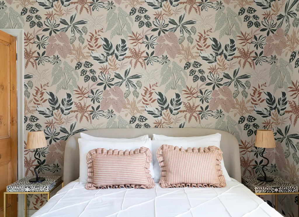The Leafy Solarium wallpaper in warm sand and pine behind the bed in a bedroom