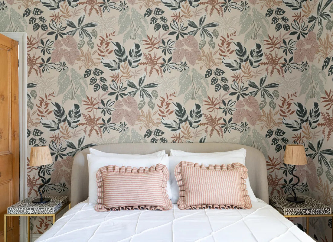 The Leafy Solarium wallpaper in warm sand and pine behind the bed in a bedroom