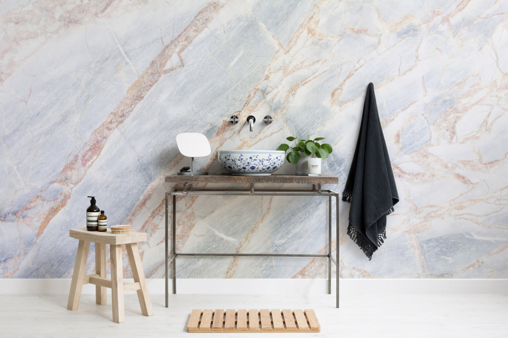 The Marble Fissure mural in pale stone and bronze in a bathroom