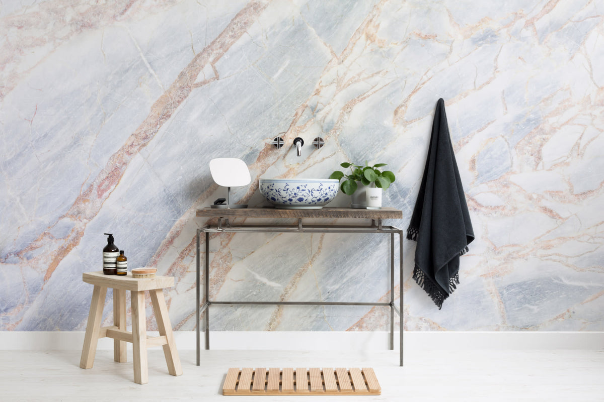 The Marble Fissure mural in pale stone and bronze in a bathroom