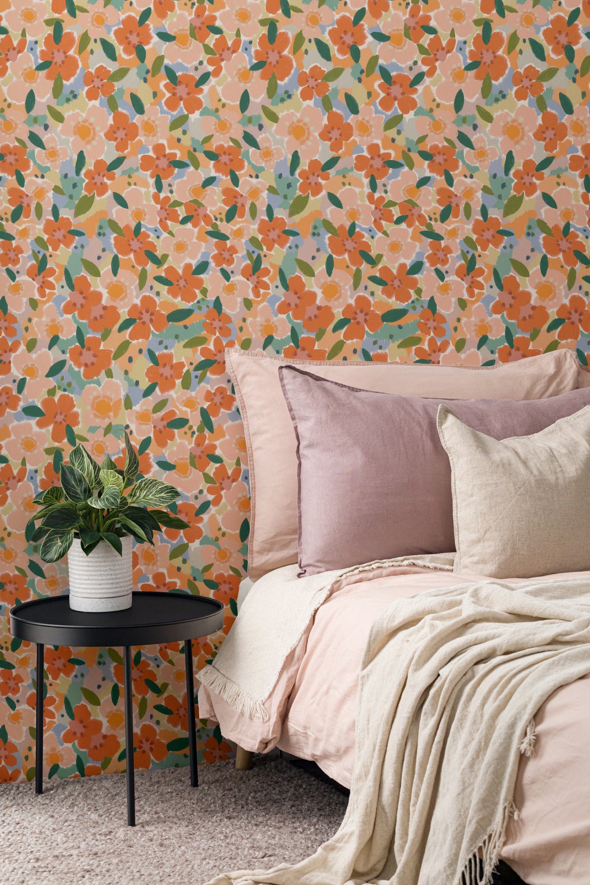 The Marmalade Bloom wallpaper in tangerine and blush behind the bed in a bedroom