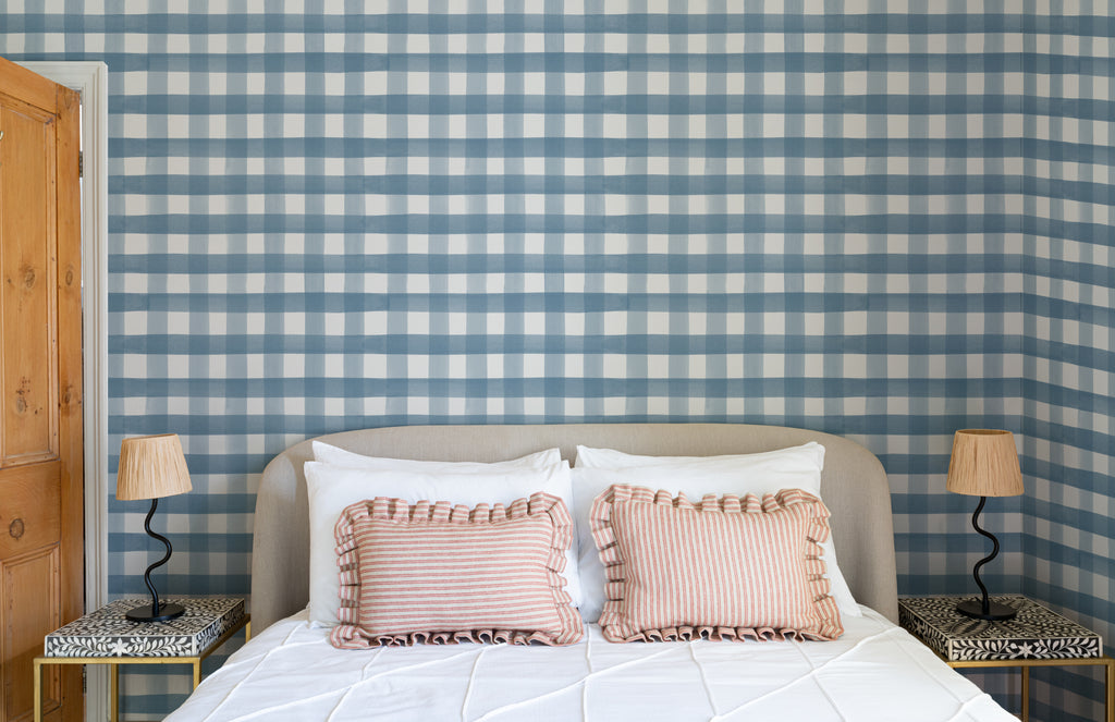The Meadow Gingham wallpaper in navy and chambray behind the bed in a bedroom