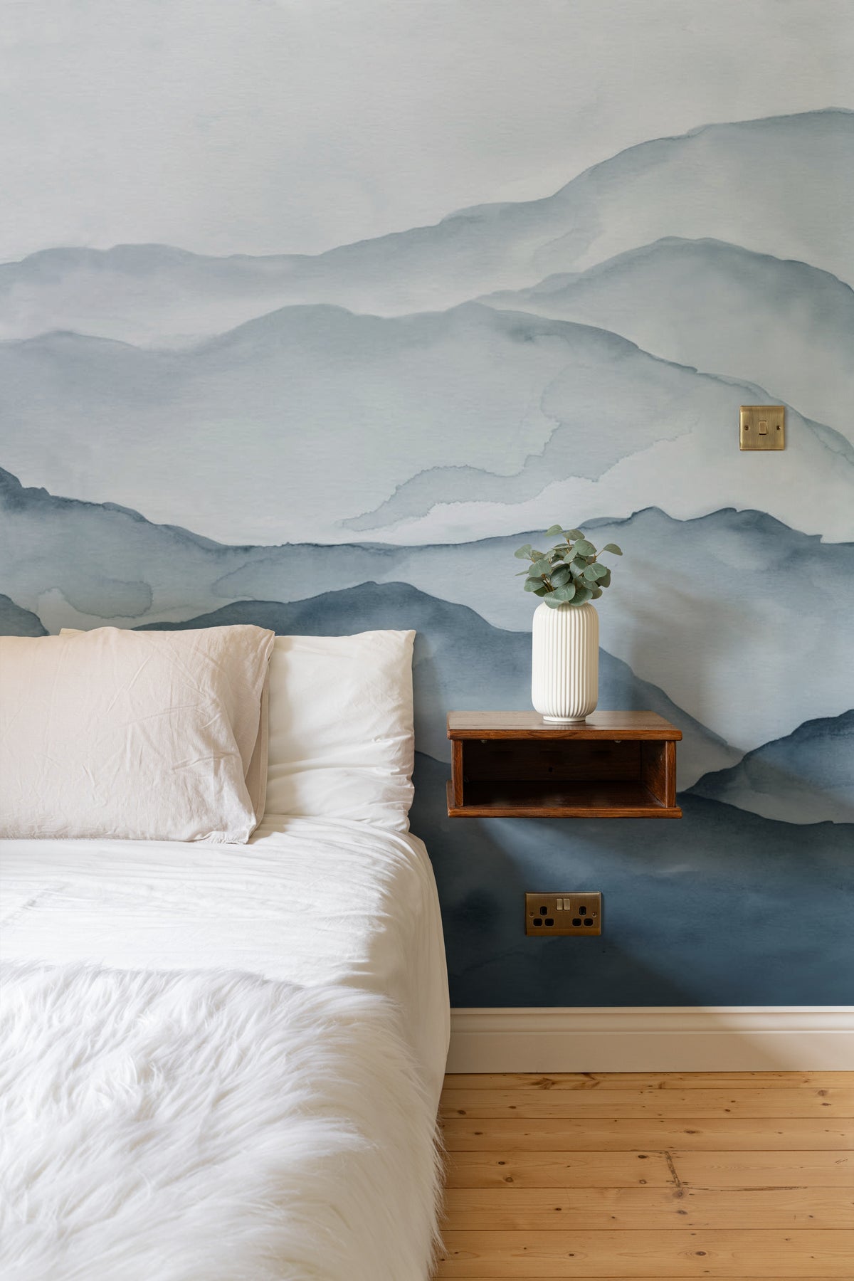 The Misted Ranges mural in ink and ice blue behind the bed in a bedroom
