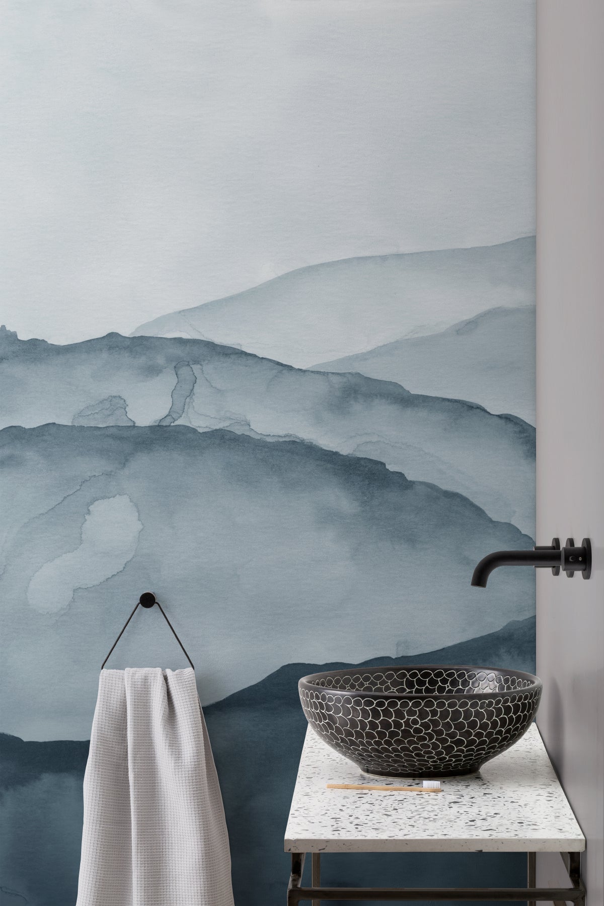 The Misted Ranges mural in ink and ice blue behind seating in a living room