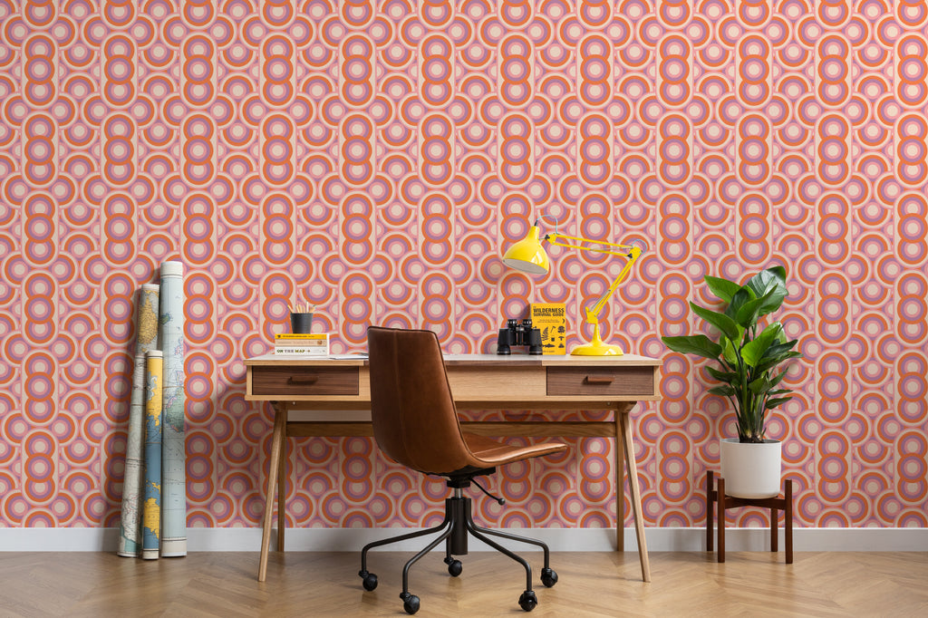 The Mod Portico wallpaper in tangerine and pink behind a desk in a home office