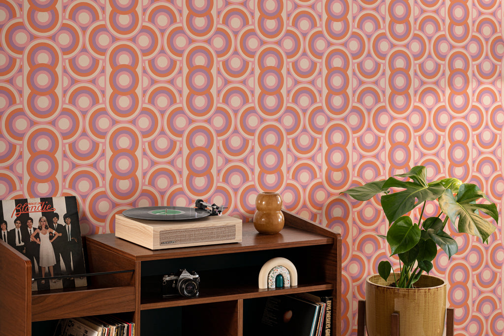 The Mod Portico wallpaper in tangerine and pink as a backdrop to styled furniture