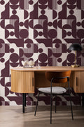 The Modernist Quadrant wallpaper in burgundy plum behind a desk in a home office