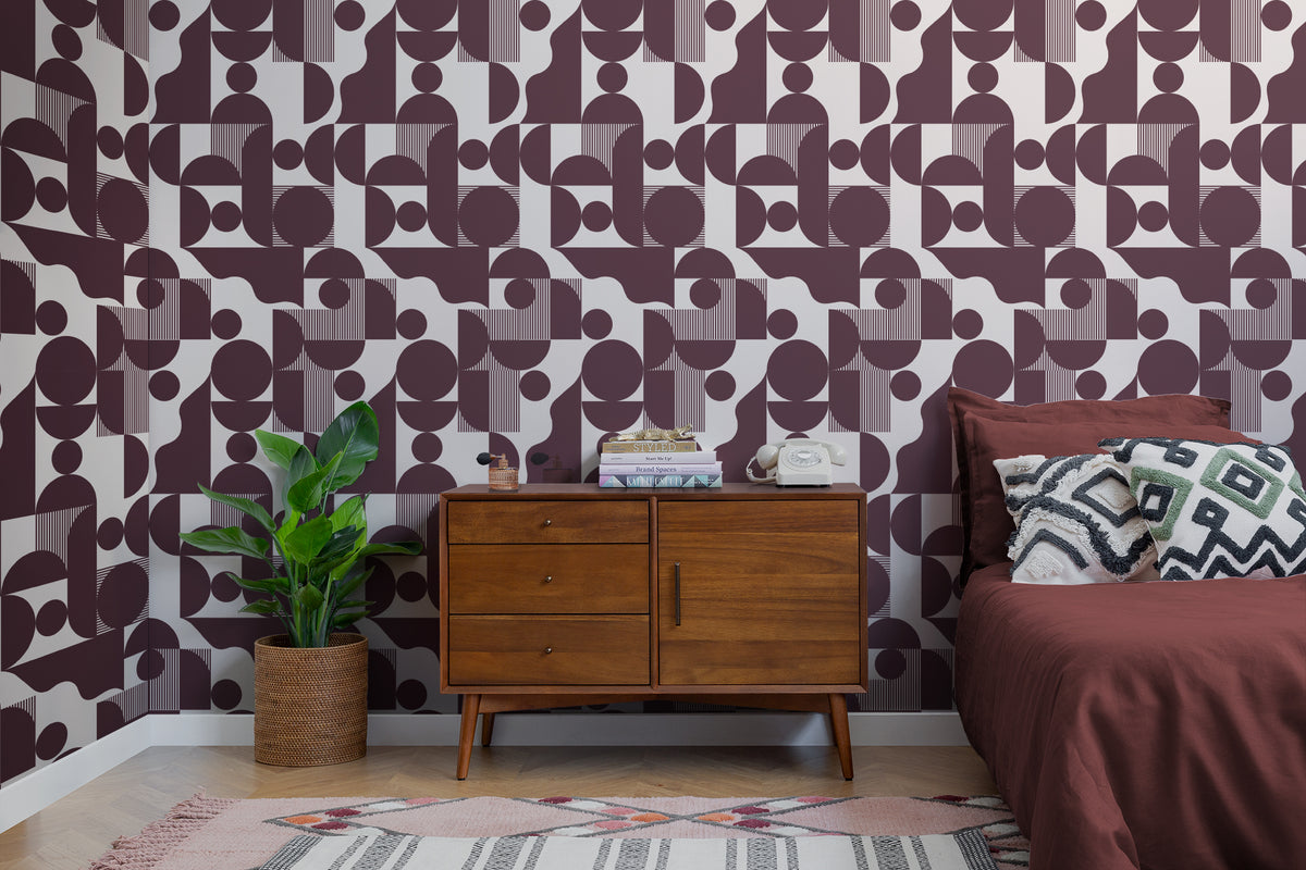 The Modernist Quadrant wallpaper in burgundy plum as a backdrop to styled furniture