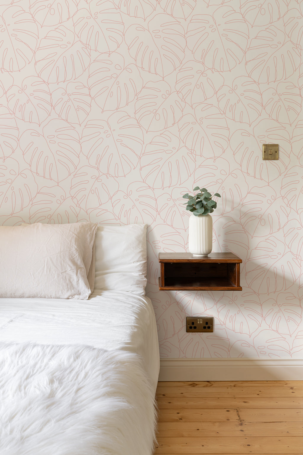 The Monstera Loggia wallpaper in blush and cream behind a styled console