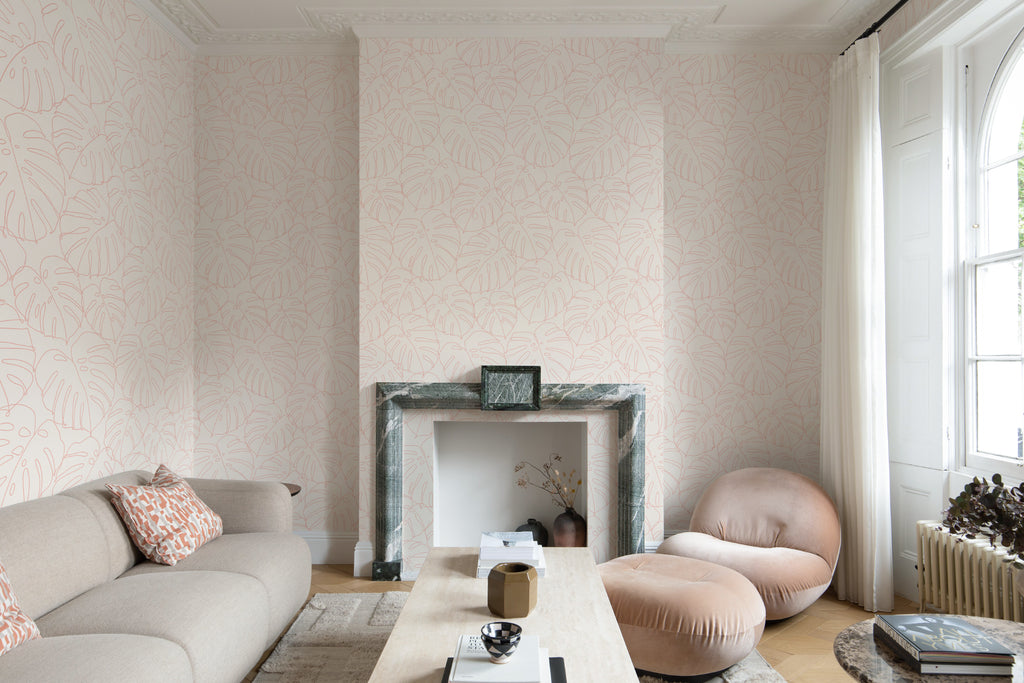 The Monstera Loggia wallpaper in blush and cream in a living room
