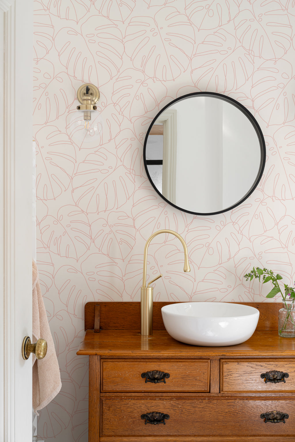 The Monstera Loggia wallpaper in blush and cream in a bathroom