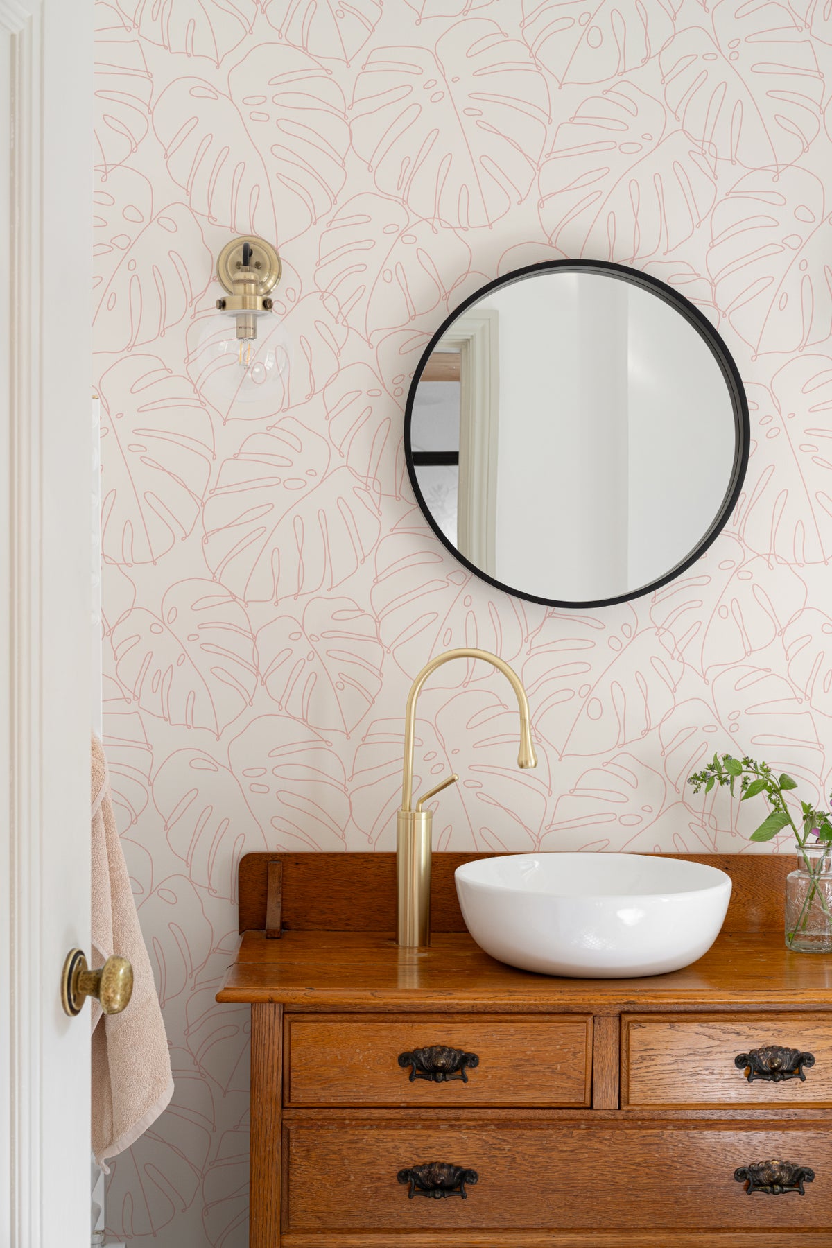 The Monstera Loggia wallpaper in blush and cream in a bathroom