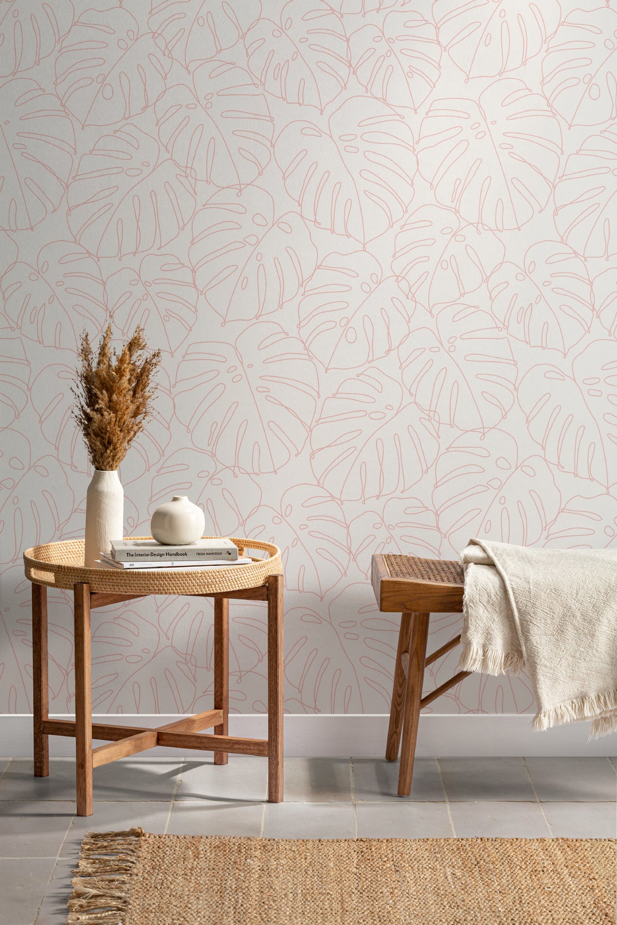 The Monstera Loggia wallpaper in blush and cream as a backdrop to styled furniture