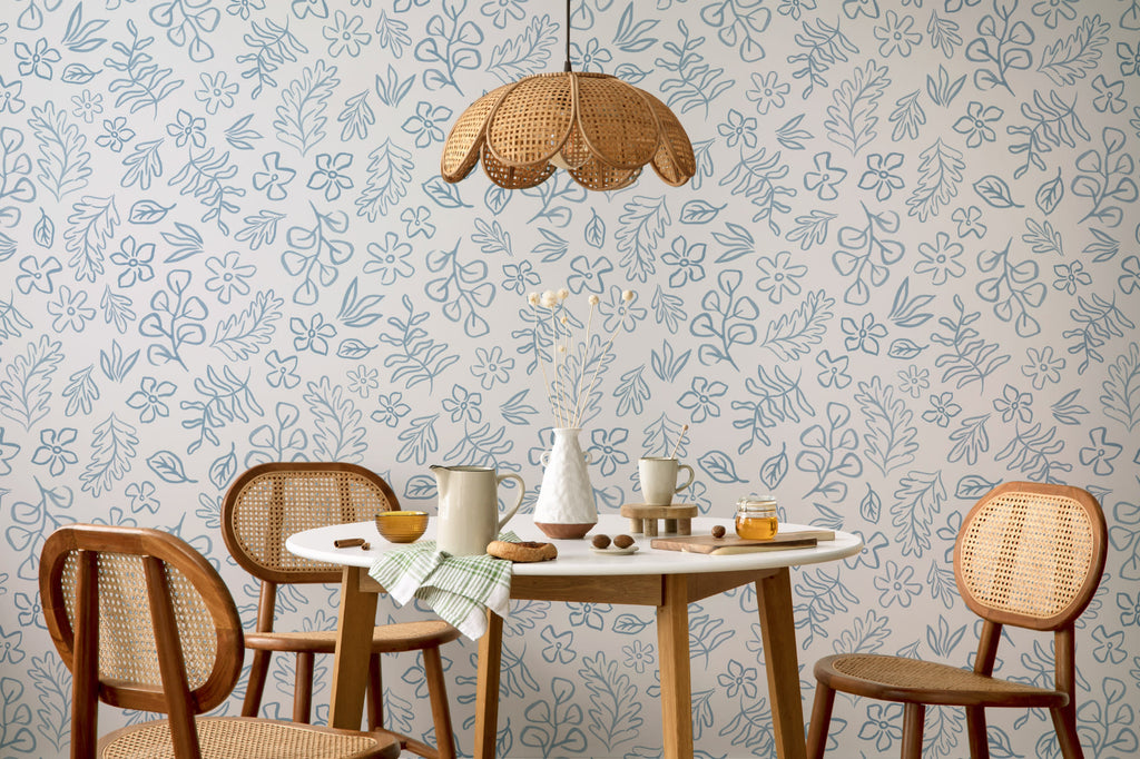 The Nordic Bough wallpaper in soft denim blue behind a dining table