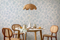 The Nordic Bough wallpaper in soft denim blue behind a dining table