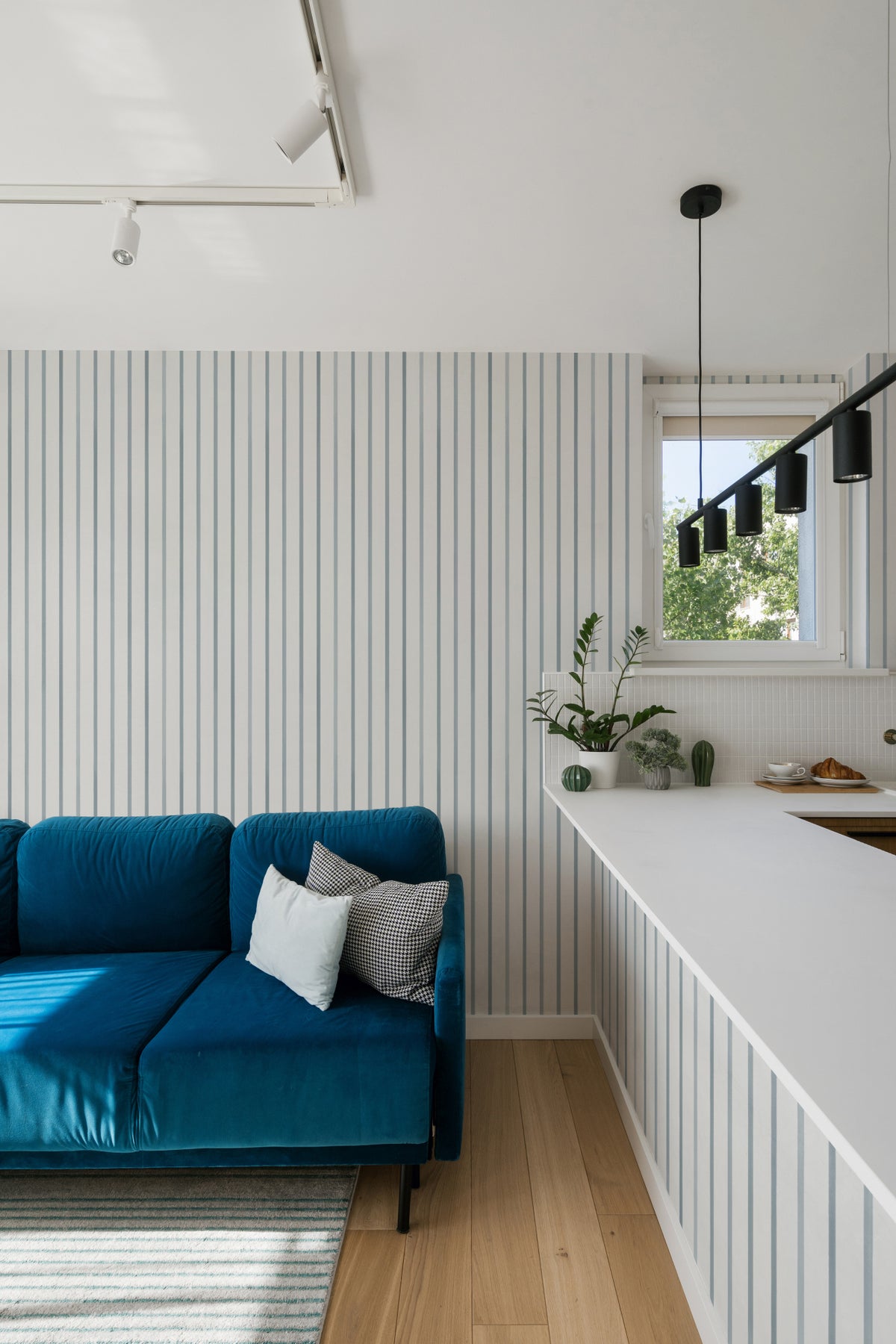 The Oxford Pinstripe mural in chambray blue behind seating in a living room
