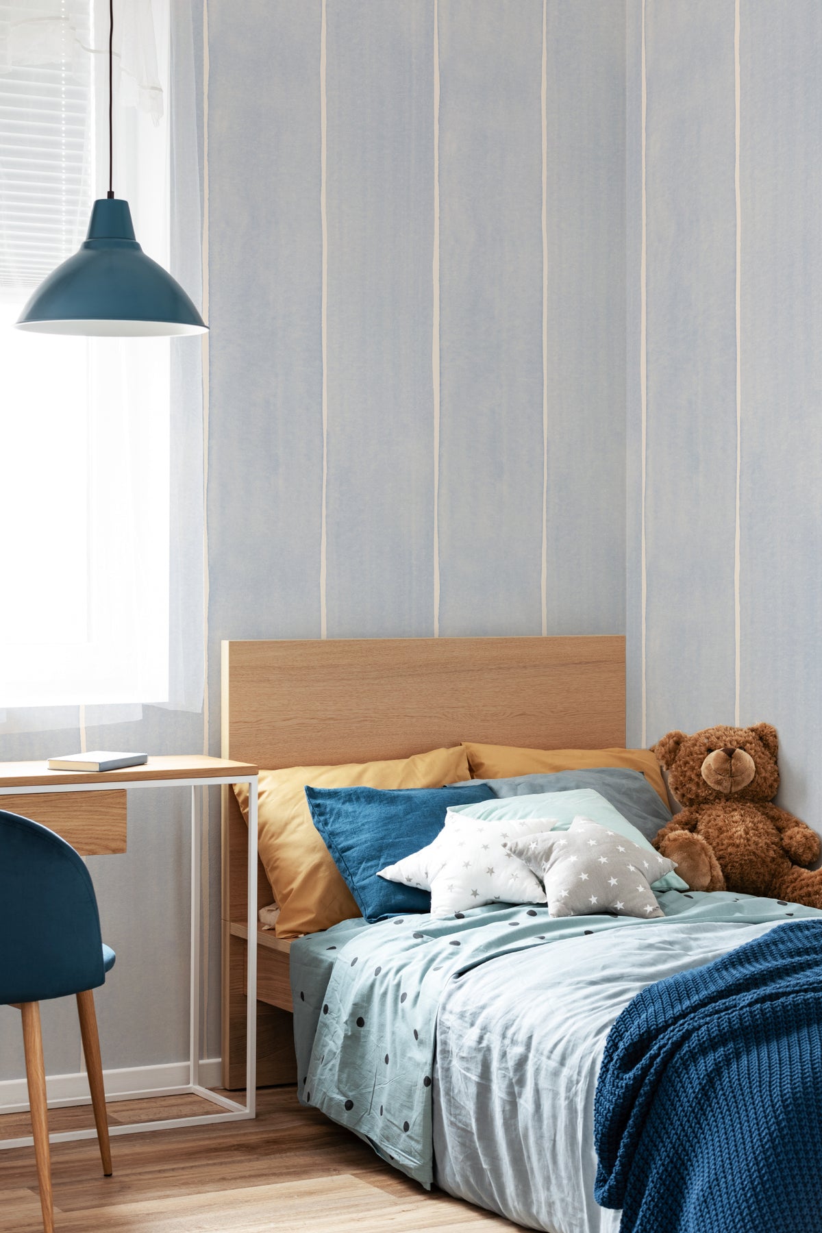 The Painted Awning wallpaper in duck egg blue behind the bed in a bedroom