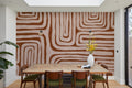 The Painted Labyrinth mural in terracotta and rose behind a dining table