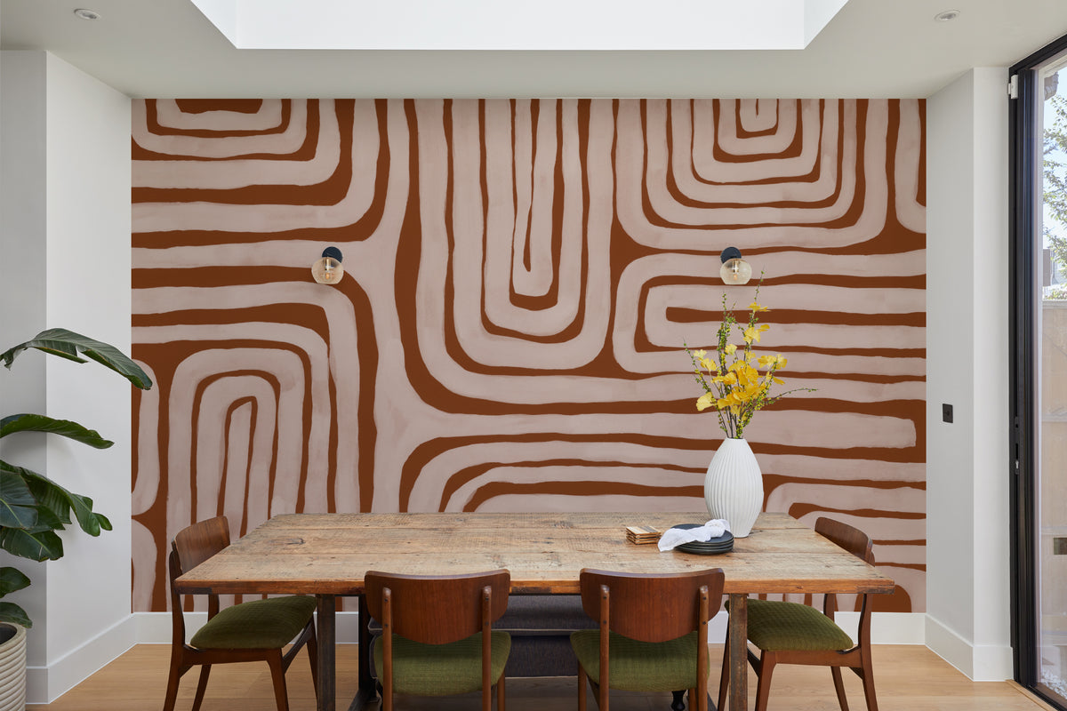 The Painted Labyrinth mural in terracotta and rose behind a dining table