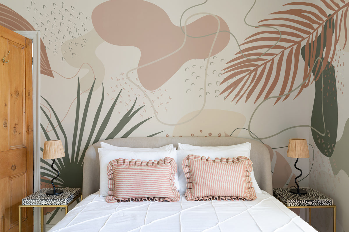 The Palm Cutout mural in clay pink and sage behind the bed in a bedroom