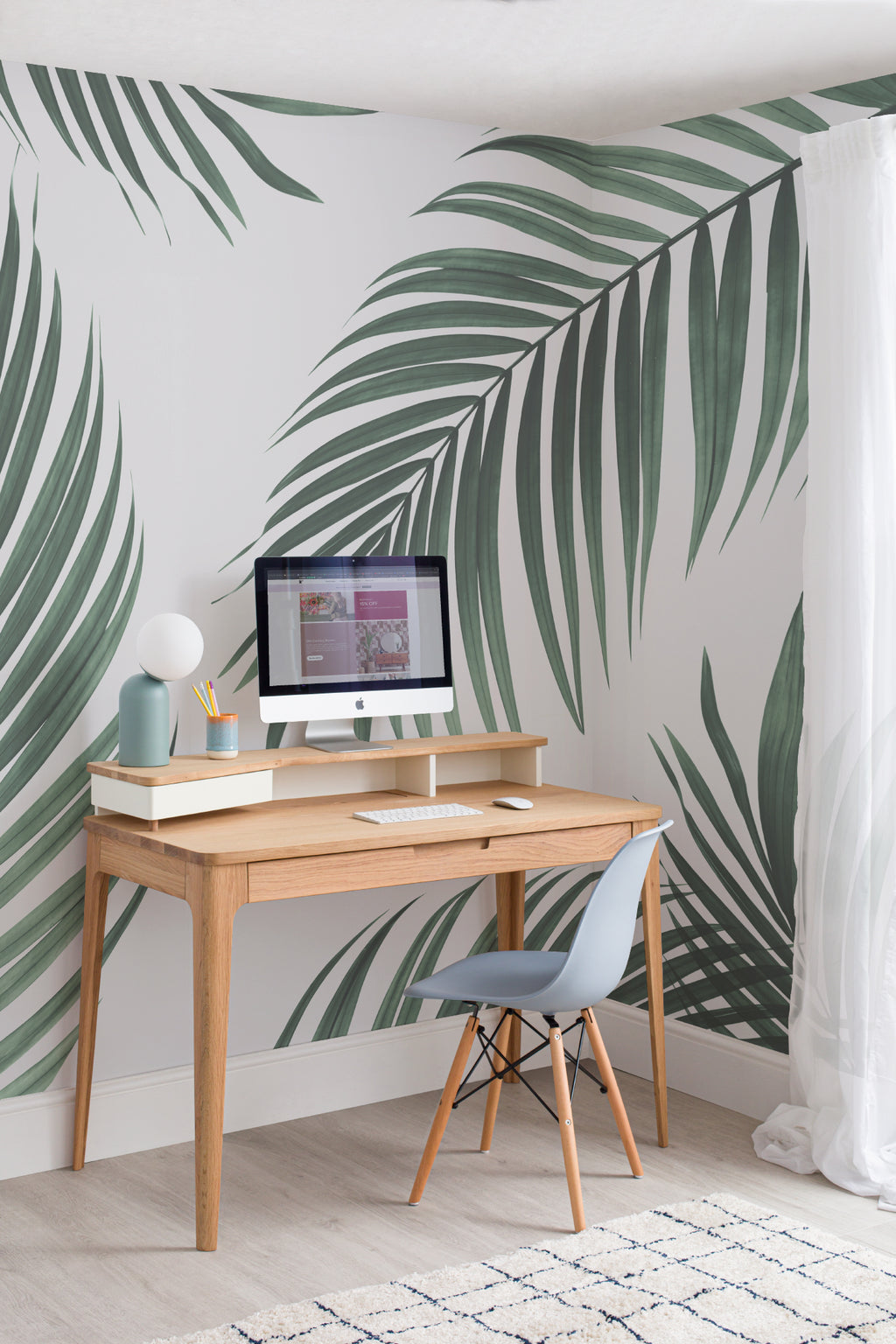 The Palm Shade mural in palm green and dove grey behind a desk in a home office